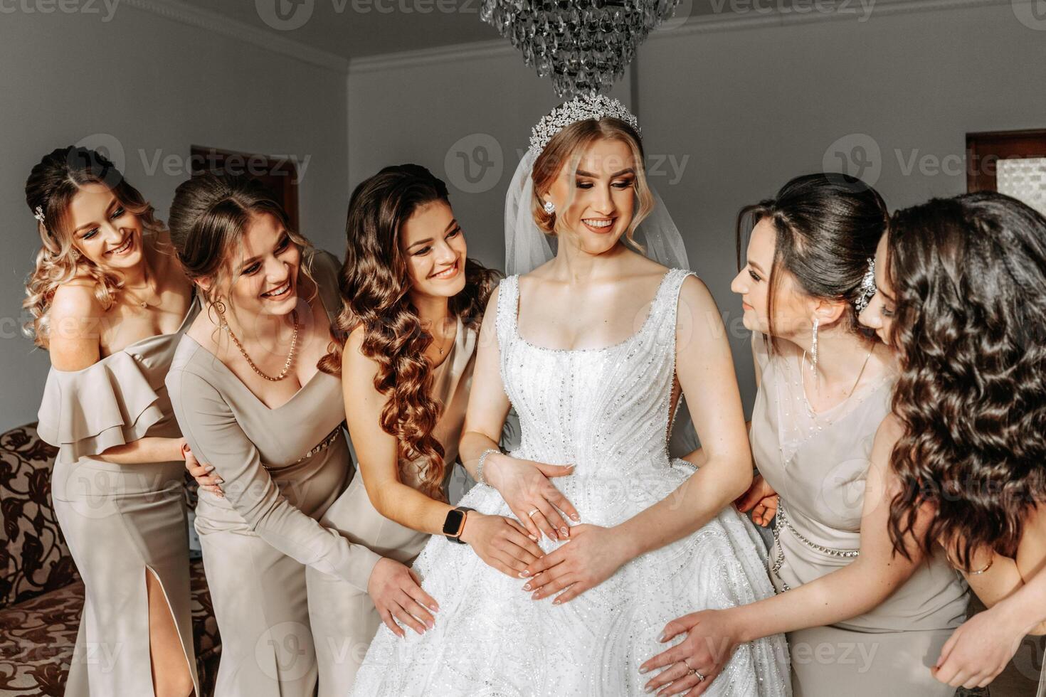 The bride in a white dress, veil and girlfriends in cream dresses, posing in beautiful lighting. Morning of the bride photo