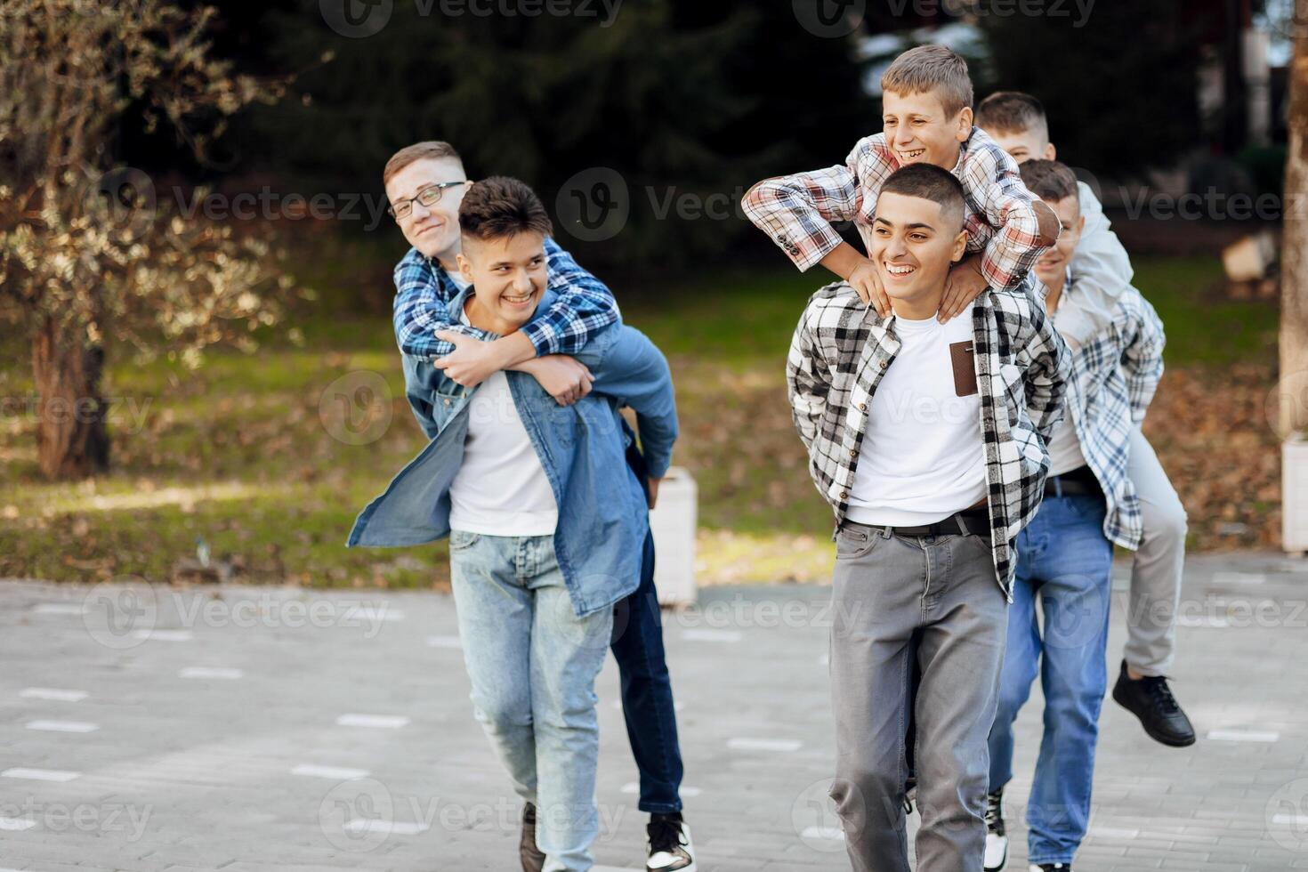 A group of teenagers have fun and rejoice, running in the park. Teenage classmates are resting against the background of autumn nature. photo