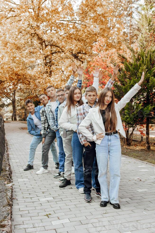 friendship, movement, action, freedom and people concept - group of happy teenagers or school friends posing and having fun outdoors against nature or forest background. photo