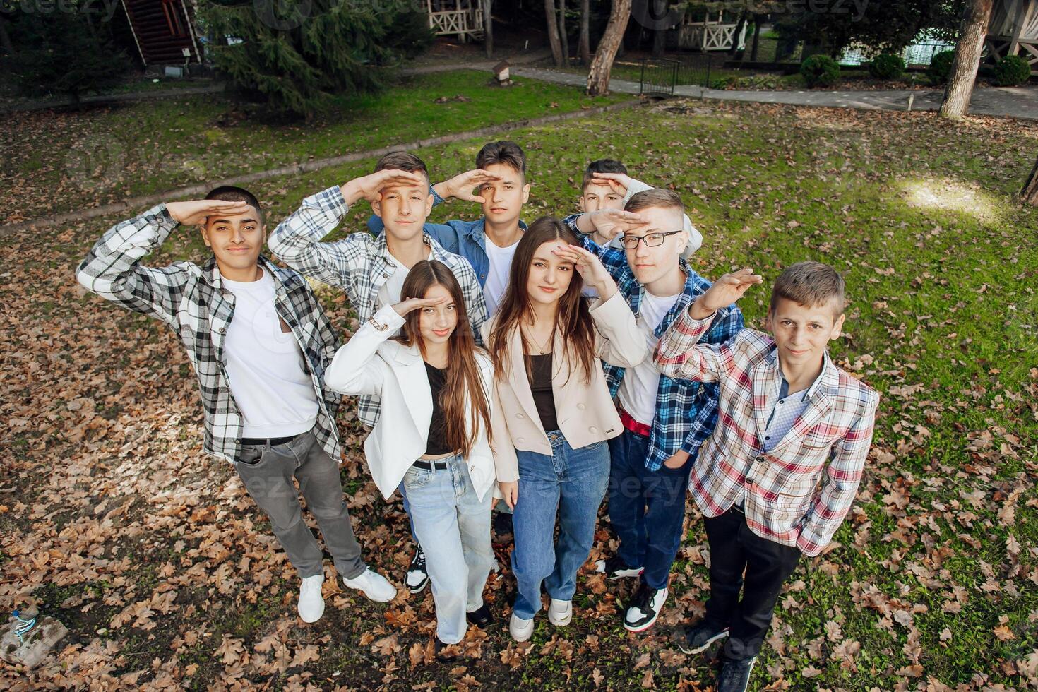 friendship, movement, action, freedom and people concept - group of happy teenagers or school friends posing and having fun outdoors against nature or forest background. photo