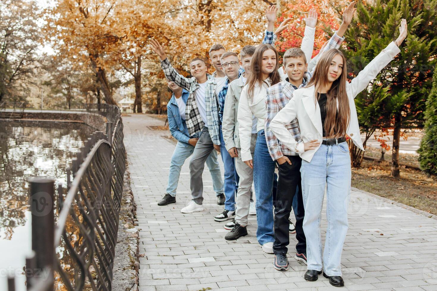 friendship, movement, action, freedom and people concept - group of happy teenagers or school friends posing and having fun outdoors against nature or forest background. photo