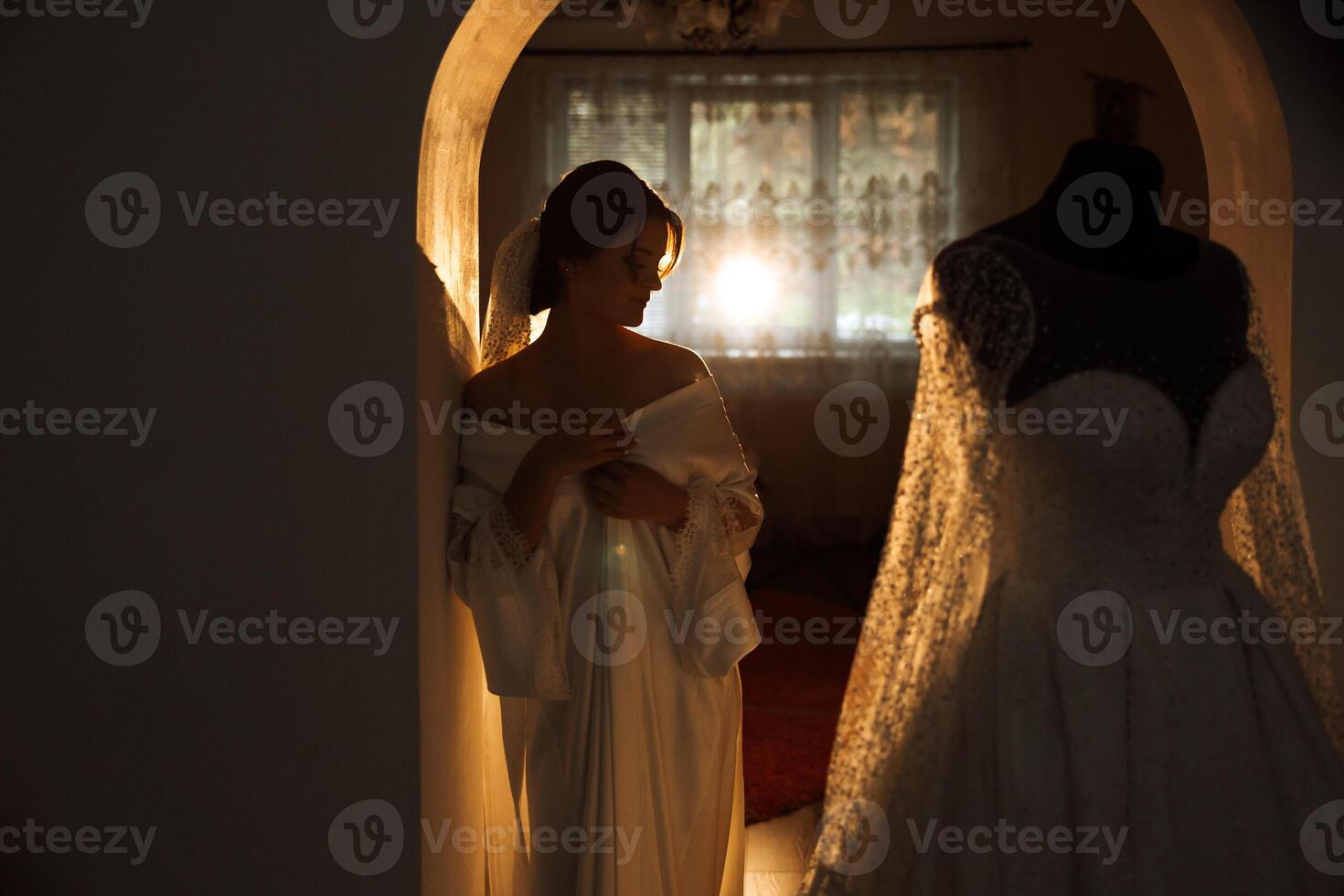 A beautiful brunette bride with a tiara in her hair is getting ready for the wedding in a beautiful robe in boudoir style. Close-up wedding portrait, photo. photo
