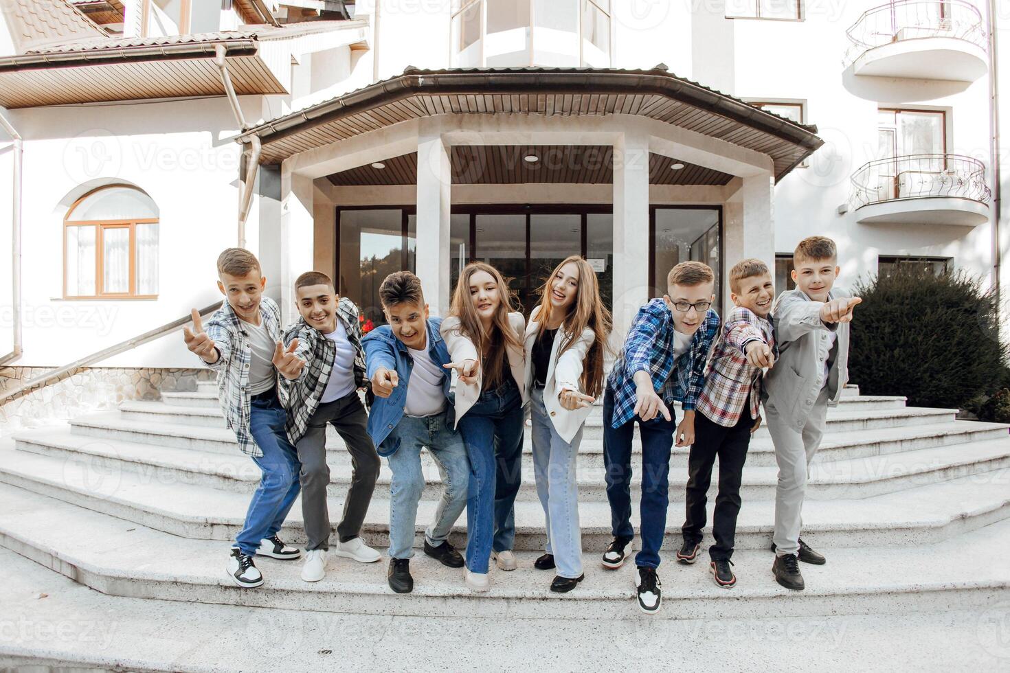 friendship, movement, action, freedom and people concept - a group of happy teenagers or school friends posing and having fun outdoors on the background of an educational institution. photo