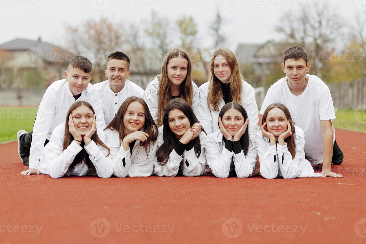 A group of many happy teenagers dressed in the same outfit having fun and posing in a stadium near a college. Concept of friendship, moments of happiness. School friendship photo