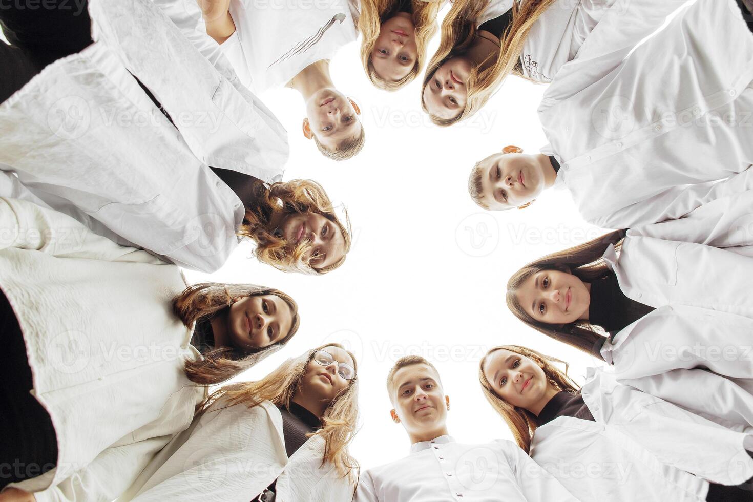 grande grupo de sonriente joven personas de pie, abrazando, mirando a cámara. grupo de alegre Adolescente personas en un circulo mirando abajo. bajo visita ángulo. Copiar espacio. foto