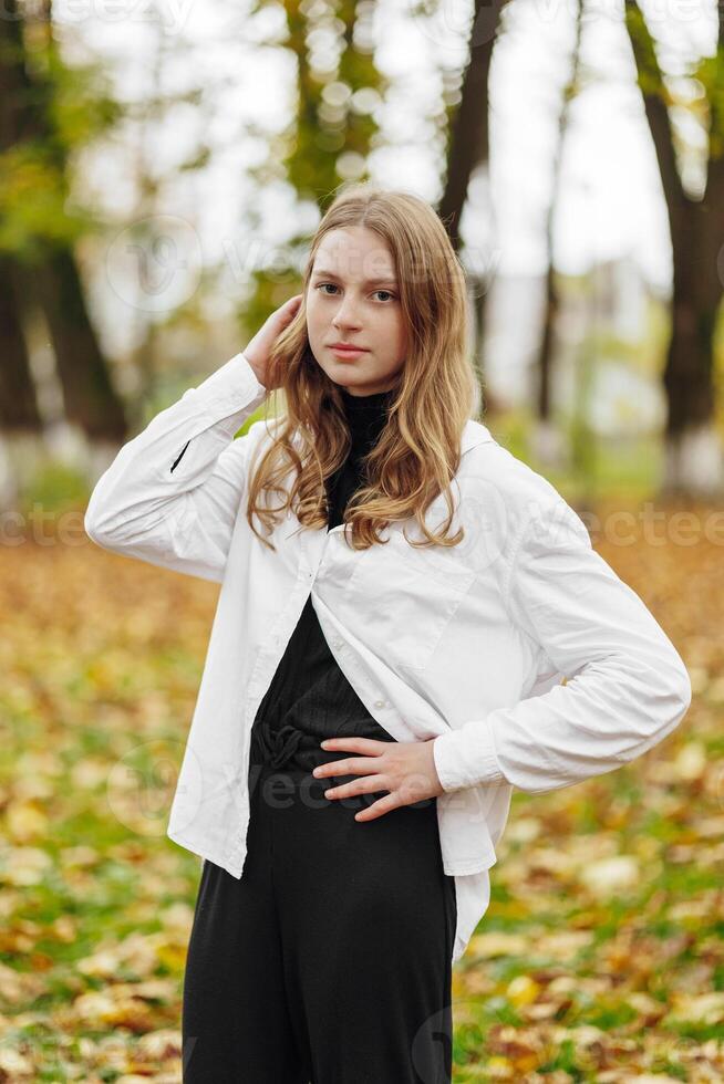 Vertical photo. Beautiful carefree young teenage girl in casual clothes. Portrait of a beautiful girl against the background of nature with a blurred background. photo