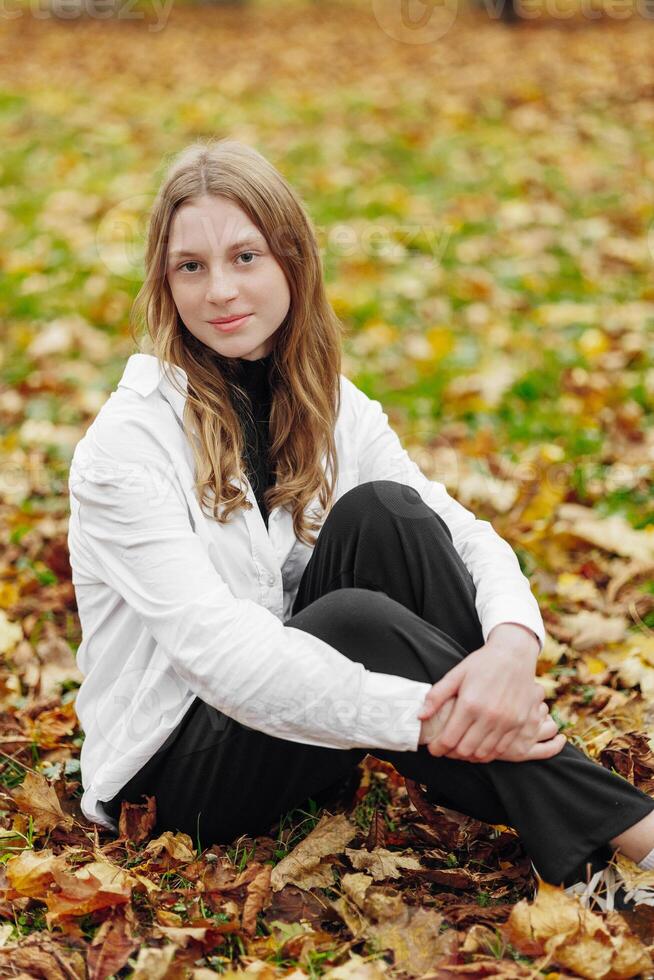 Vertical photo. Beautiful carefree young teenage girl in casual clothes. Portrait of a beautiful girl against the background of nature with a blurred background. photo