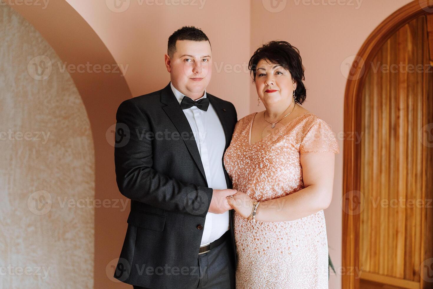 madre ayuda su adulto hijo preparar para el Boda ceremonia. un emocional y conmovedor momento a un boda. un madre abrazos su hijo foto