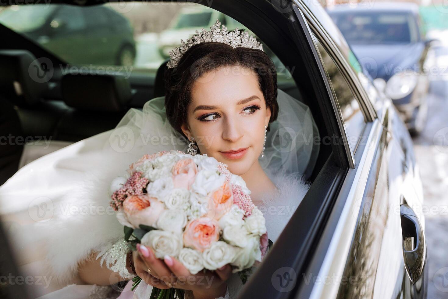 Portrait of an incredibly beautiful bride in the window of an expensive car. The bride with a bouquet of flowers looks away. photo