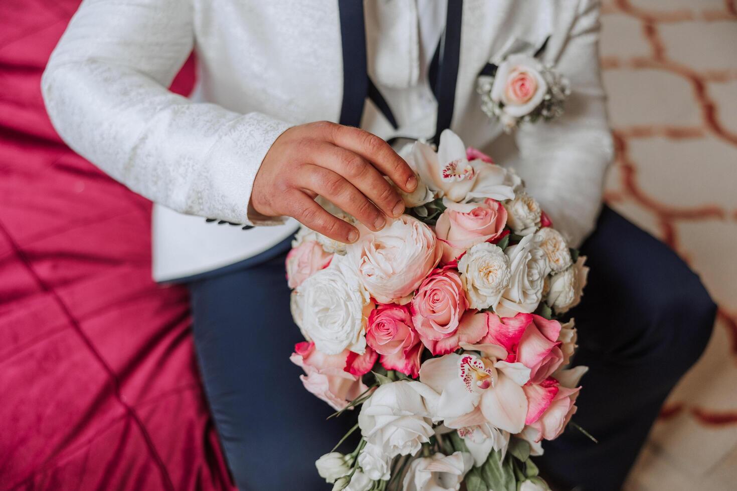 Stylish portrait of the groom with a bouquet of flowers. A man is preparing for a wedding ceremony in the morning. Groom's morning. Preparation for the groom's morning. Young and handsome groom. photo