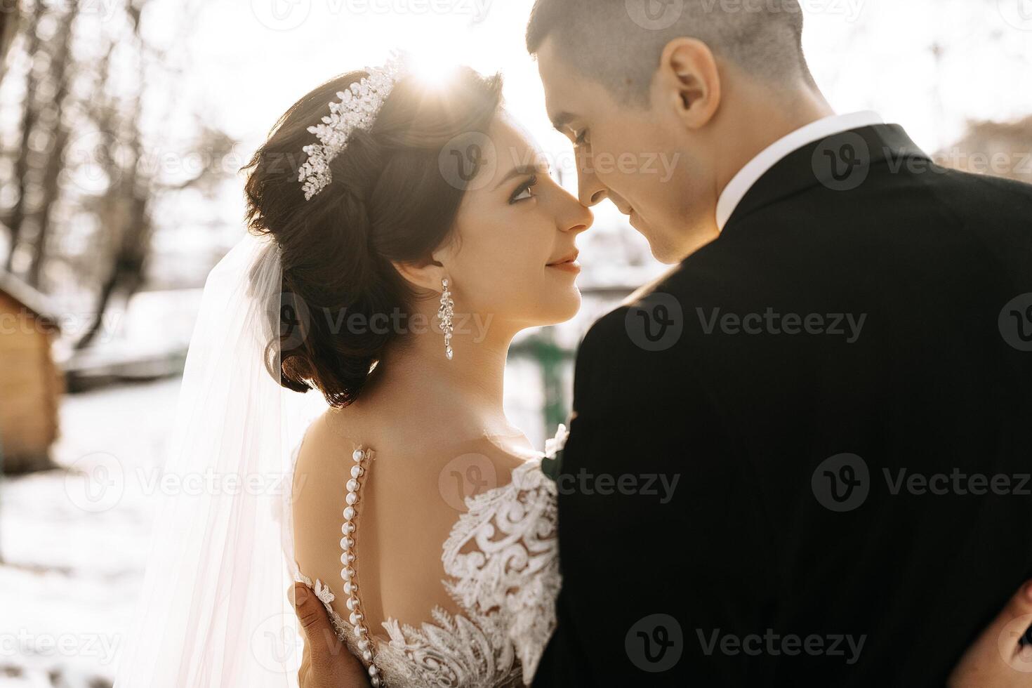 Winter wedding. A happy couple in wedding clothes are hugging and smiling in a winter park covered with snow on their wedding day. Winter love story of a beautiful couple in snowy winter weather photo