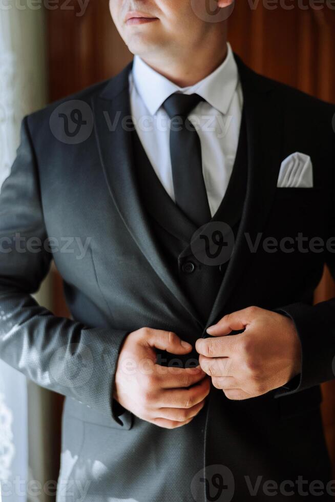 el hombre sujeta el botones en su chaqueta. el novio es preparando para el Boda ceremonia. detallado de cerca foto de manos