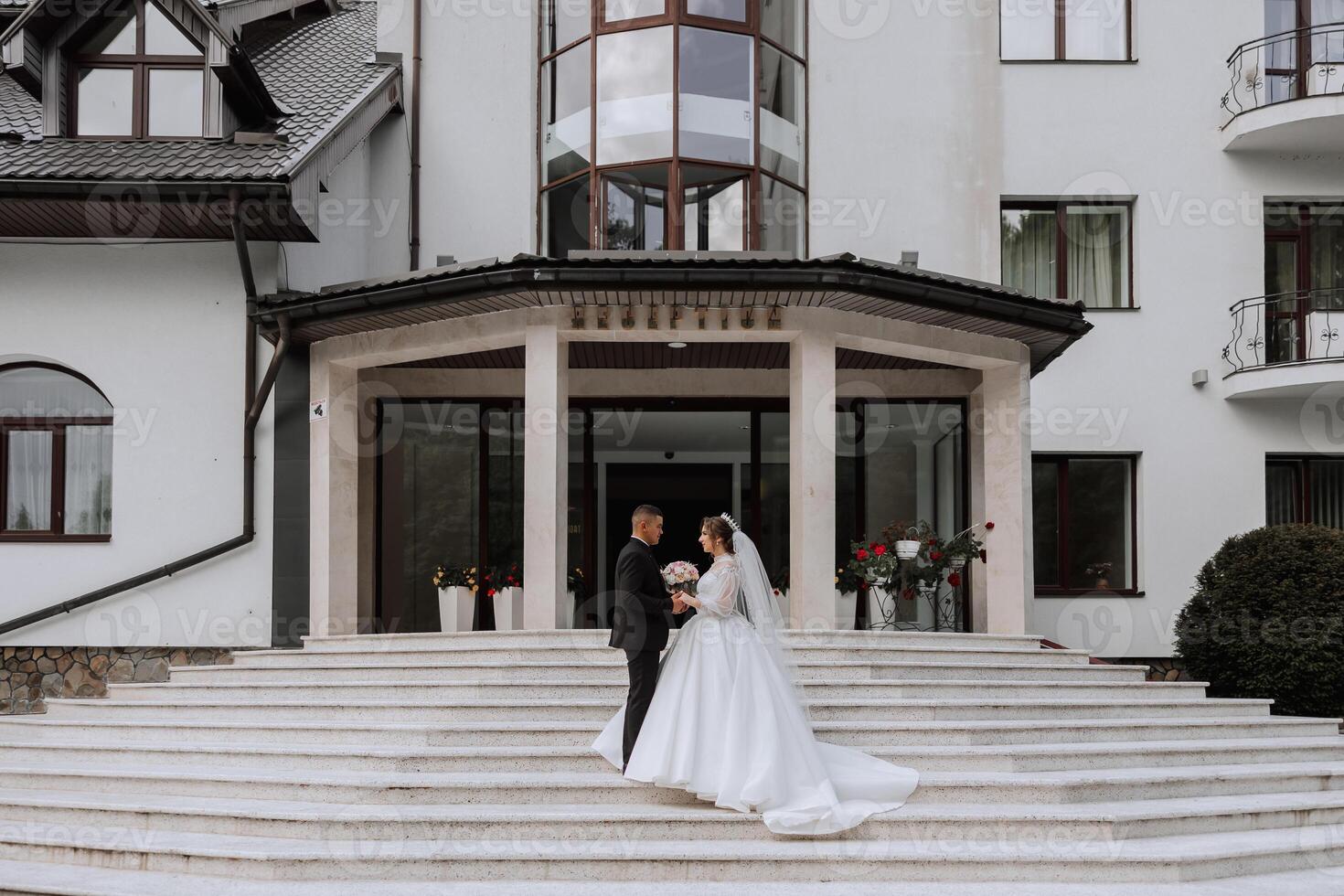 portrait of the newlyweds in classic wedding clothes on a large beautiful staircase. the concept of stores and sales of goods for the bride and groom. photo