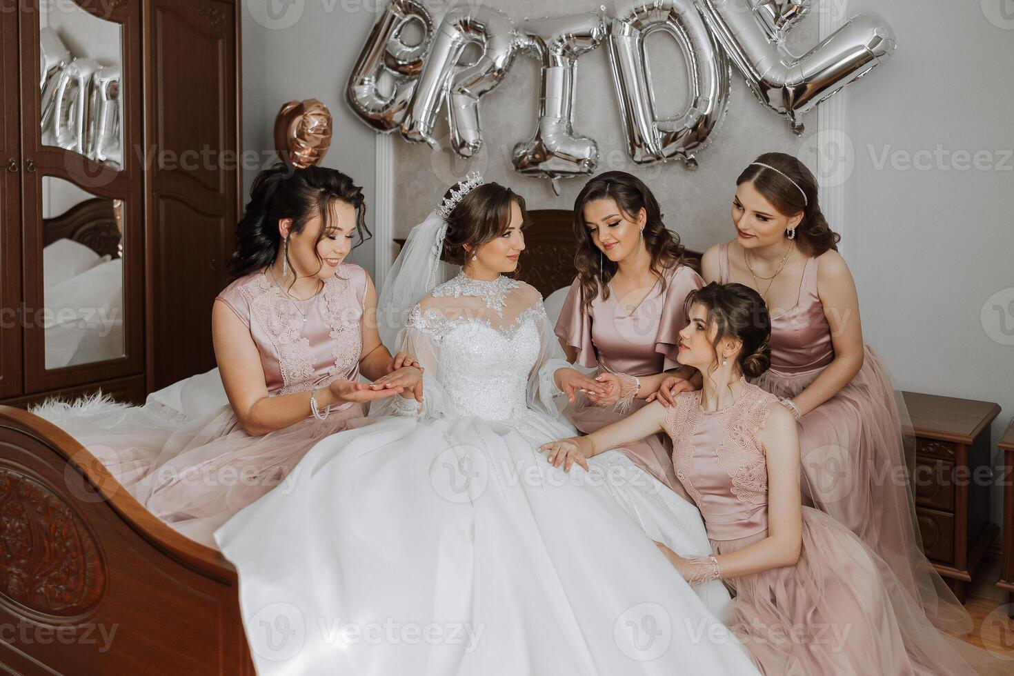 Friends rejoice with the bride in the morning. They take pictures, smile, help the bride fasten her dress. photo