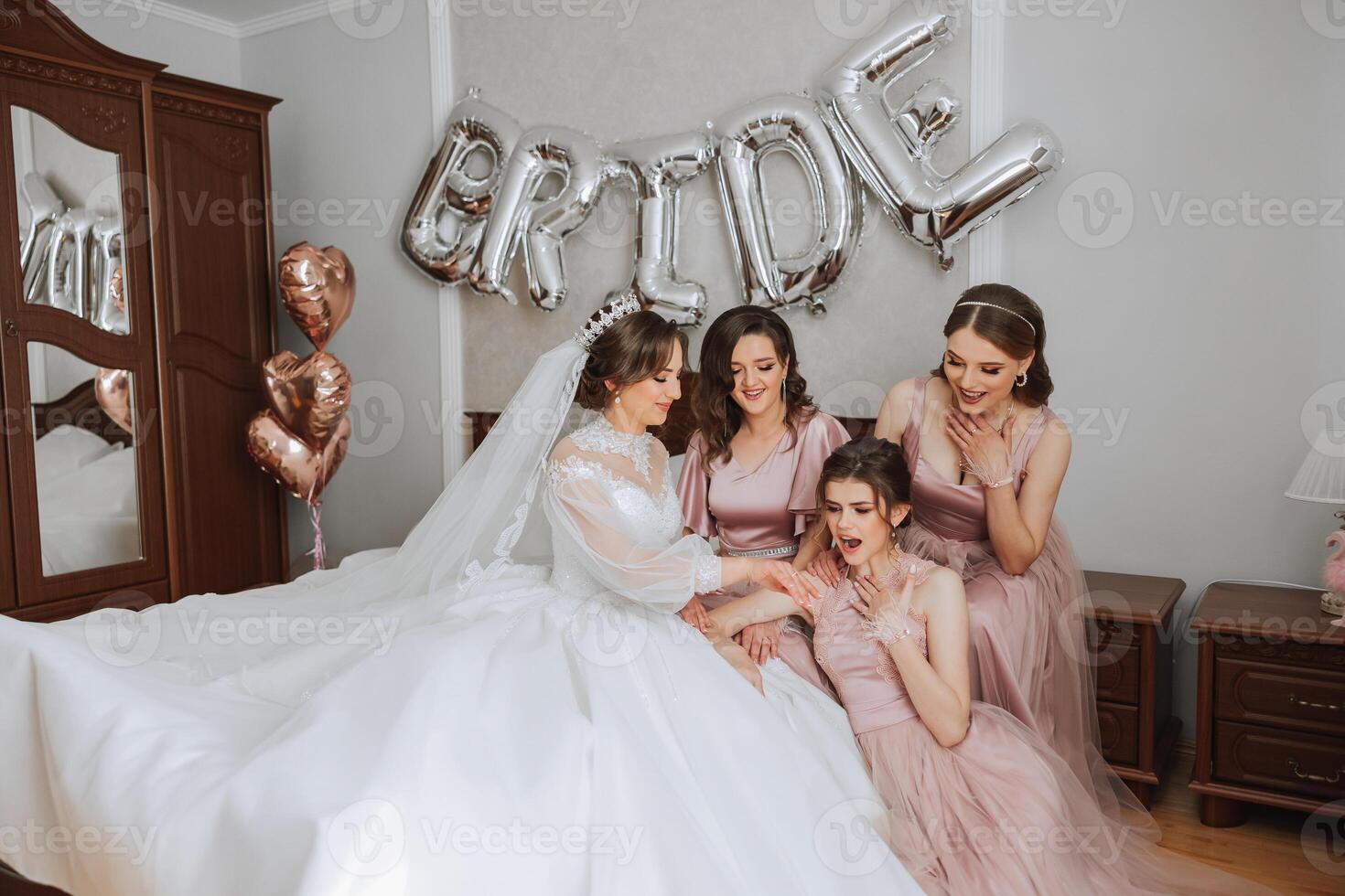 Friends rejoice with the bride in the morning. They take pictures, smile, help the bride fasten her dress. photo