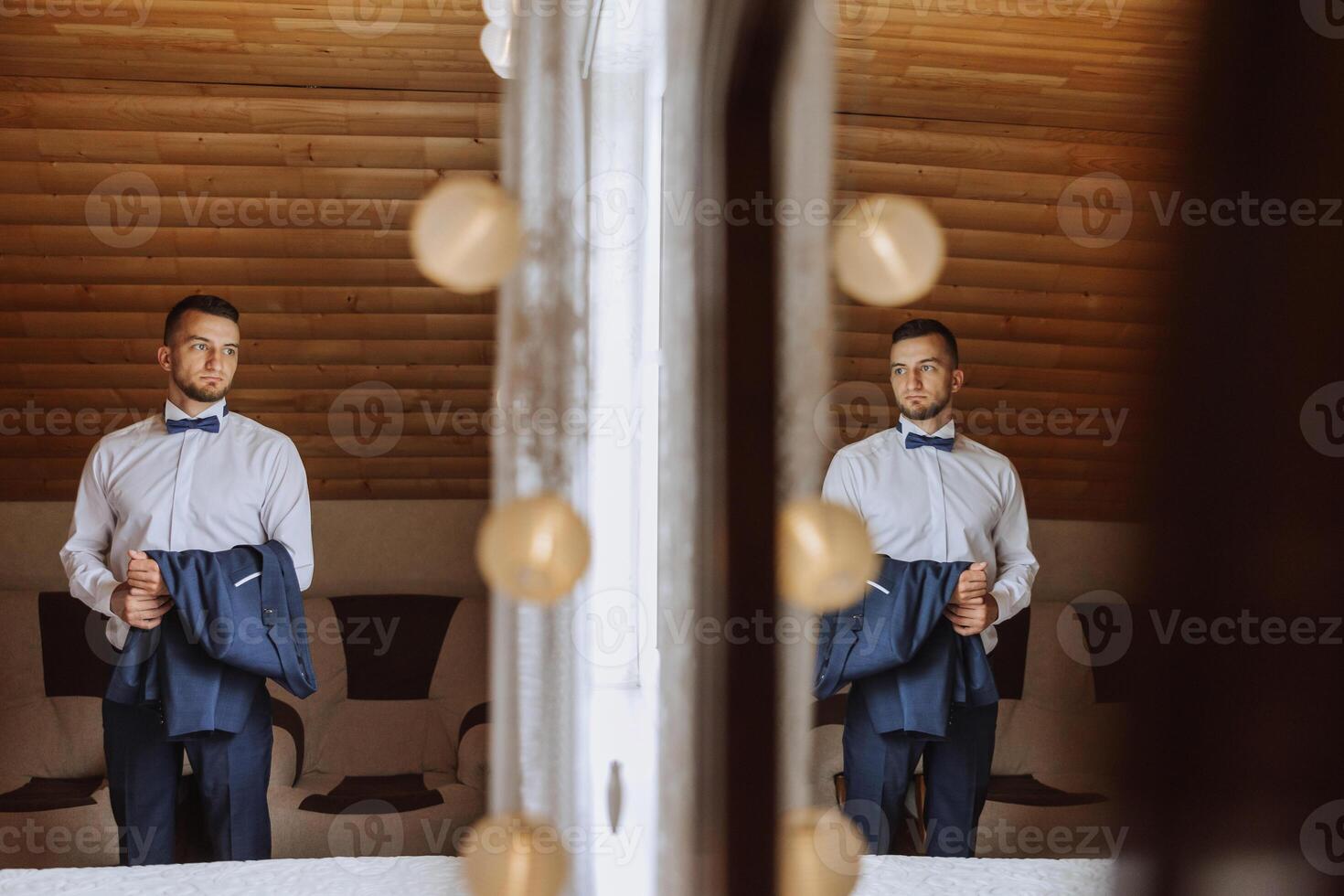elegant and luxurious man holding his jacket before dressing in hotel room with reflection in mirror. photo