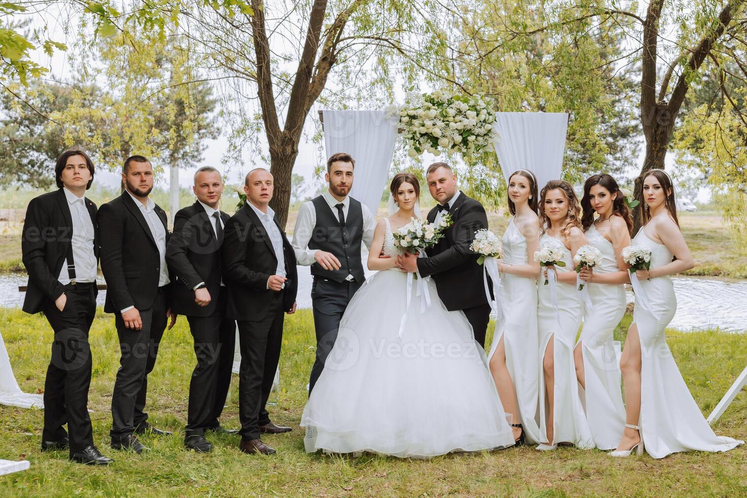 full-length portrait of the newlyweds and their friends at the wedding. The bride and groom with bridesmaids and friends of the groom are having fun and rejoicing at the wedding. photo