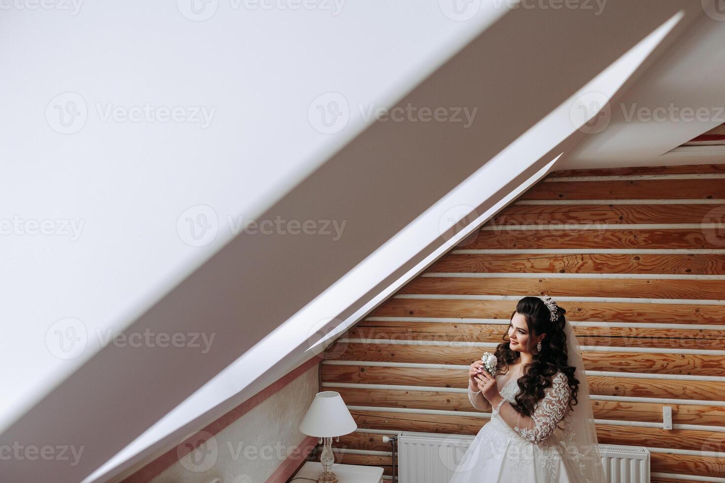 A wonderful beautiful portrait of a young bride. Beautiful bride with wedding makeup and jewelry wreath on long curly hair. Wedding photo model with brown eyes in a beautiful interior.