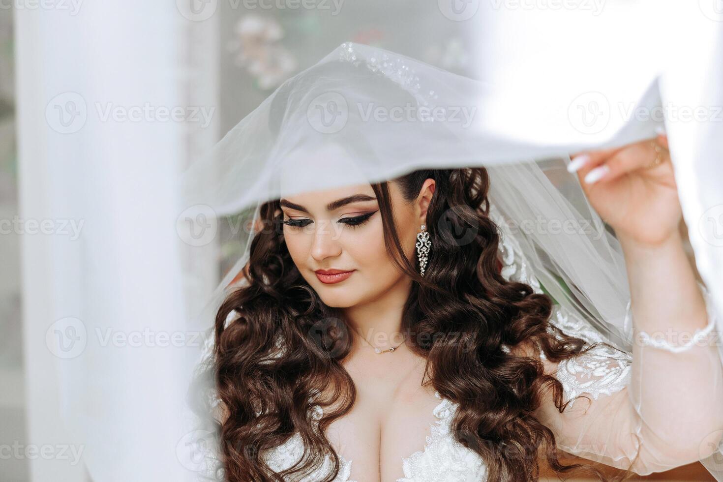 A wonderful beautiful portrait of a young bride. Beautiful bride with wedding makeup and jewelry wreath on long curly hair. Wedding photo model with brown eyes in a beautiful interior.