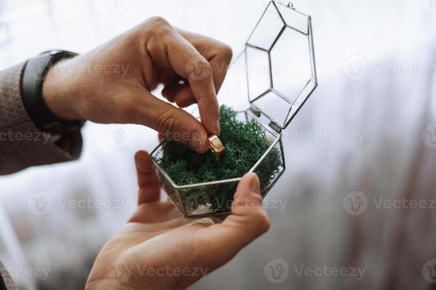 Golden wedding rings in a glass gift box, in the hands of the groom, close-up. Wedding concept. Wedding details. photo