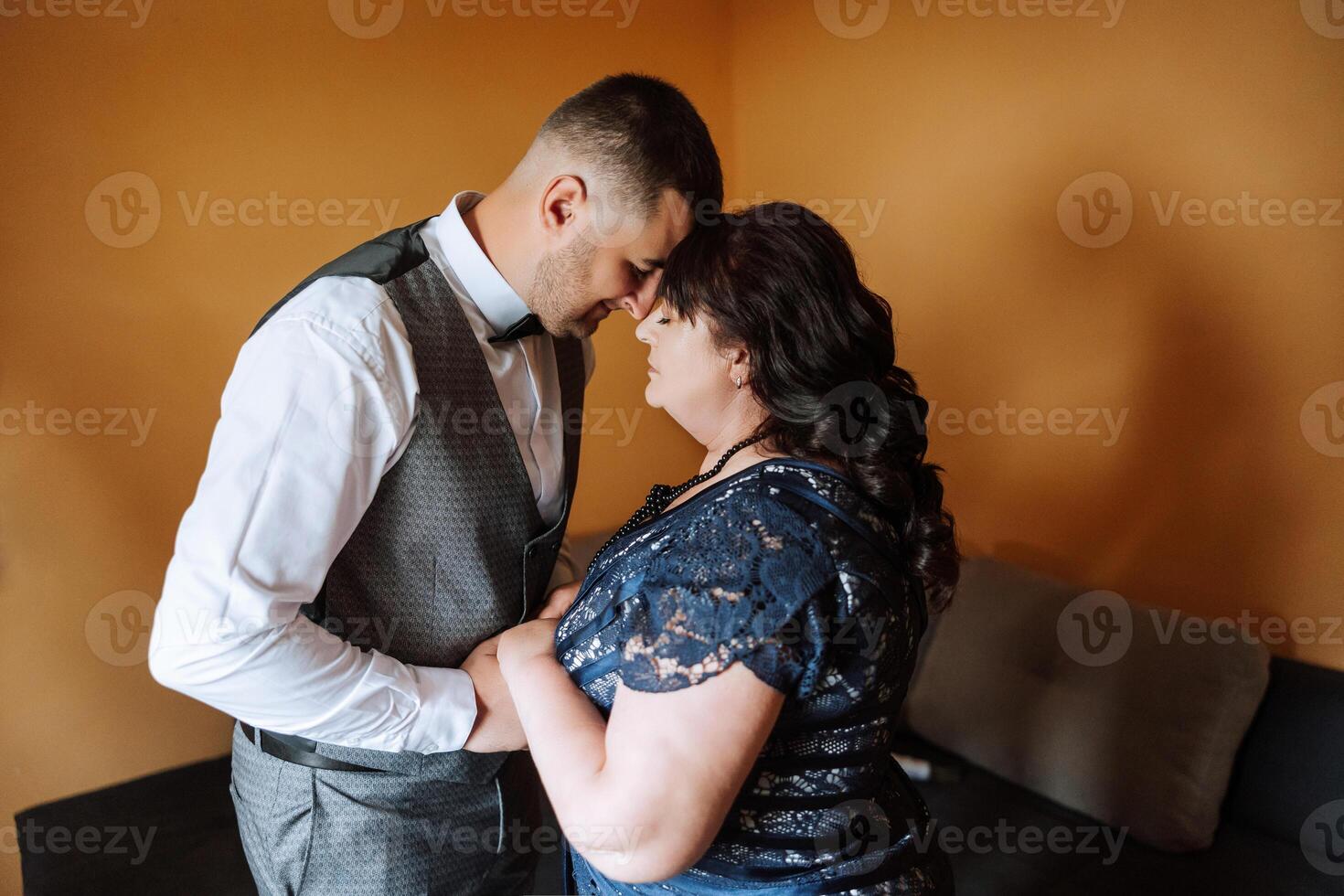 mother helps her adult son prepare for the wedding ceremony. An emotional and touching moment at a wedding. A mother hugs her son photo
