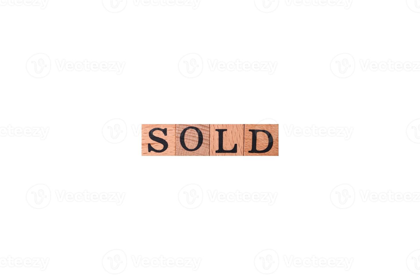 The inscription Sold made of wooden cubes on a plain background photo