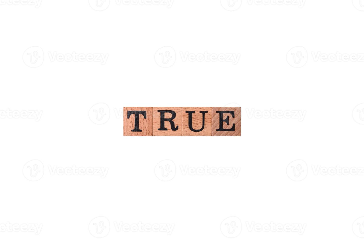 The inscription True made of wooden cubes on a plain background photo