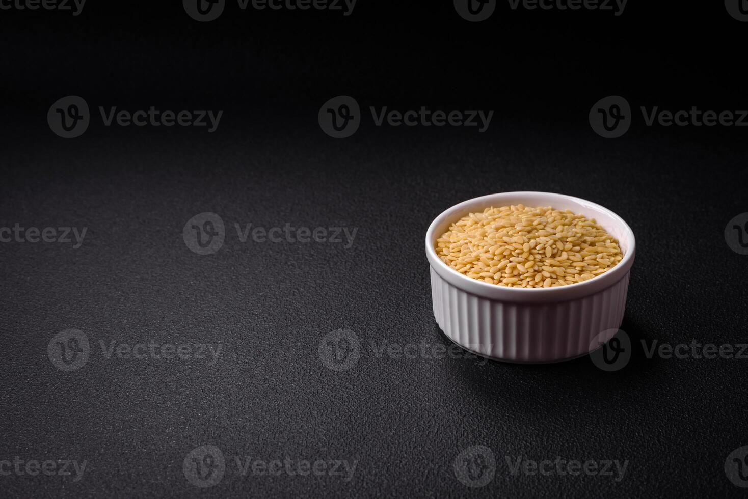 Raw risoni pasta made from durum wheat on a dark concrete background photo