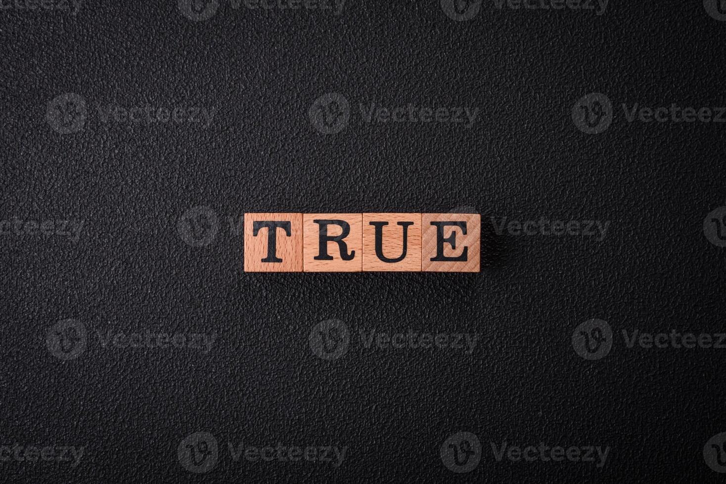 The inscription True made of wooden cubes on a plain background photo