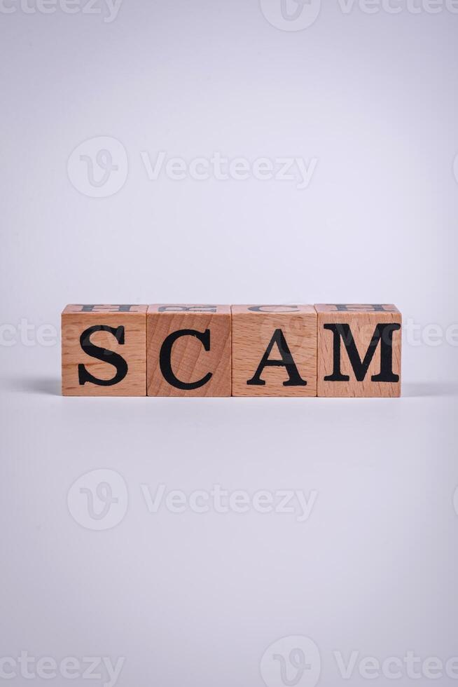 The inscription Scam made of wooden cubes on a plain background photo