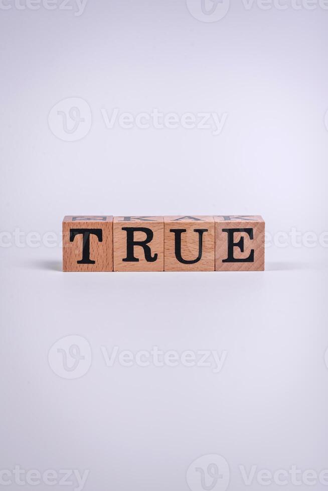 The inscription True made of wooden cubes on a plain background photo