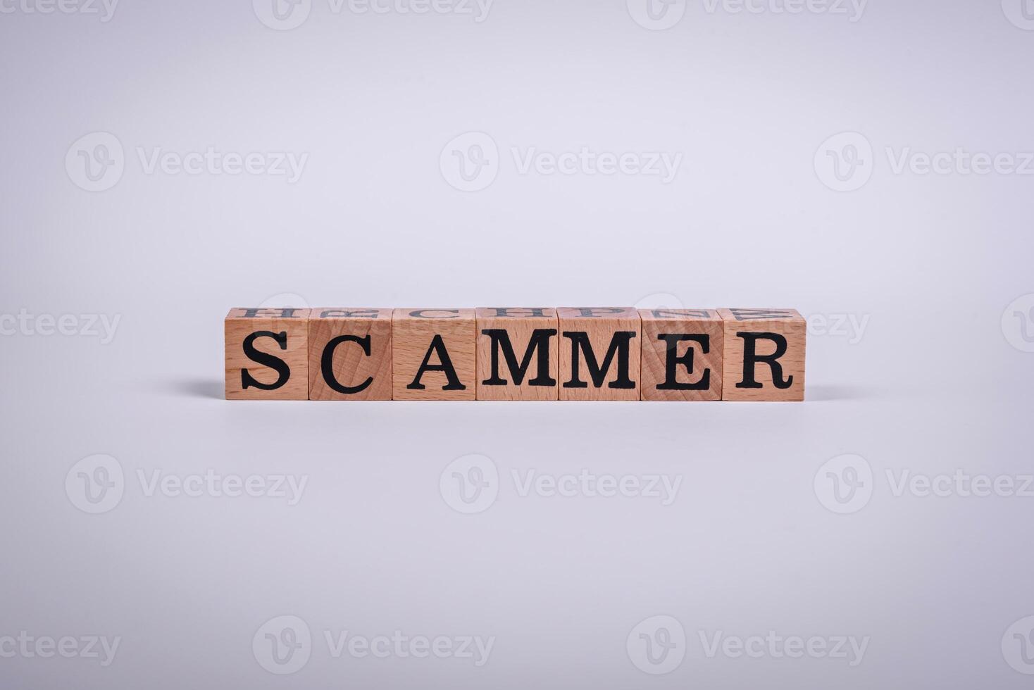The inscription Scammer made of wooden cubes on a plain background photo