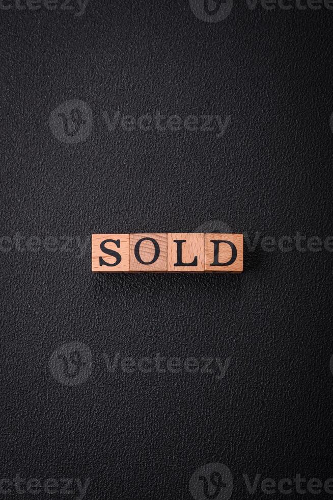 The inscription Sold made of wooden cubes on a plain background photo