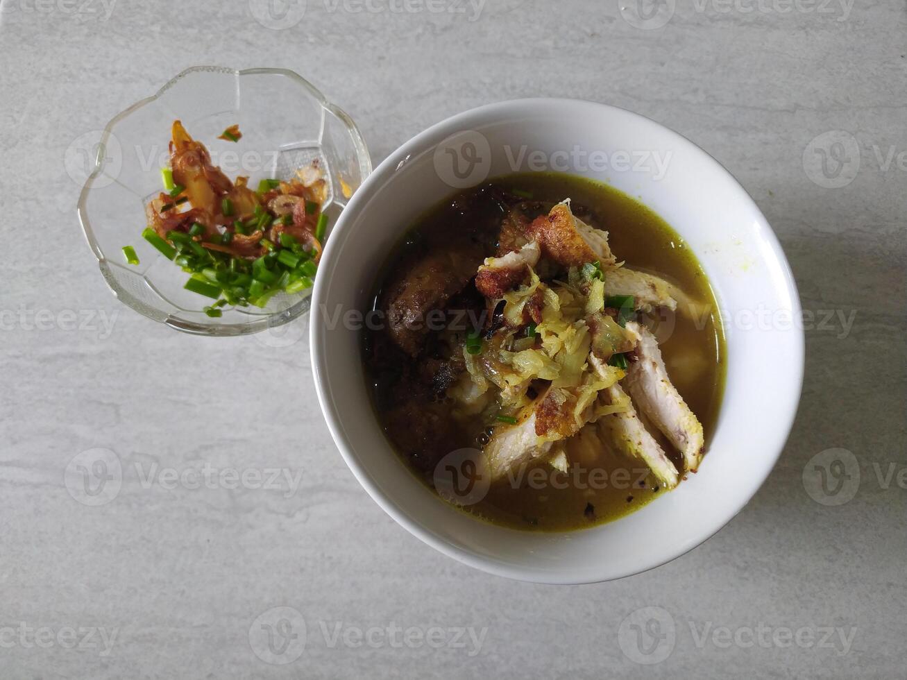 Typical Indonesian chicken porridge with sauce served in a ceramic bowl photo