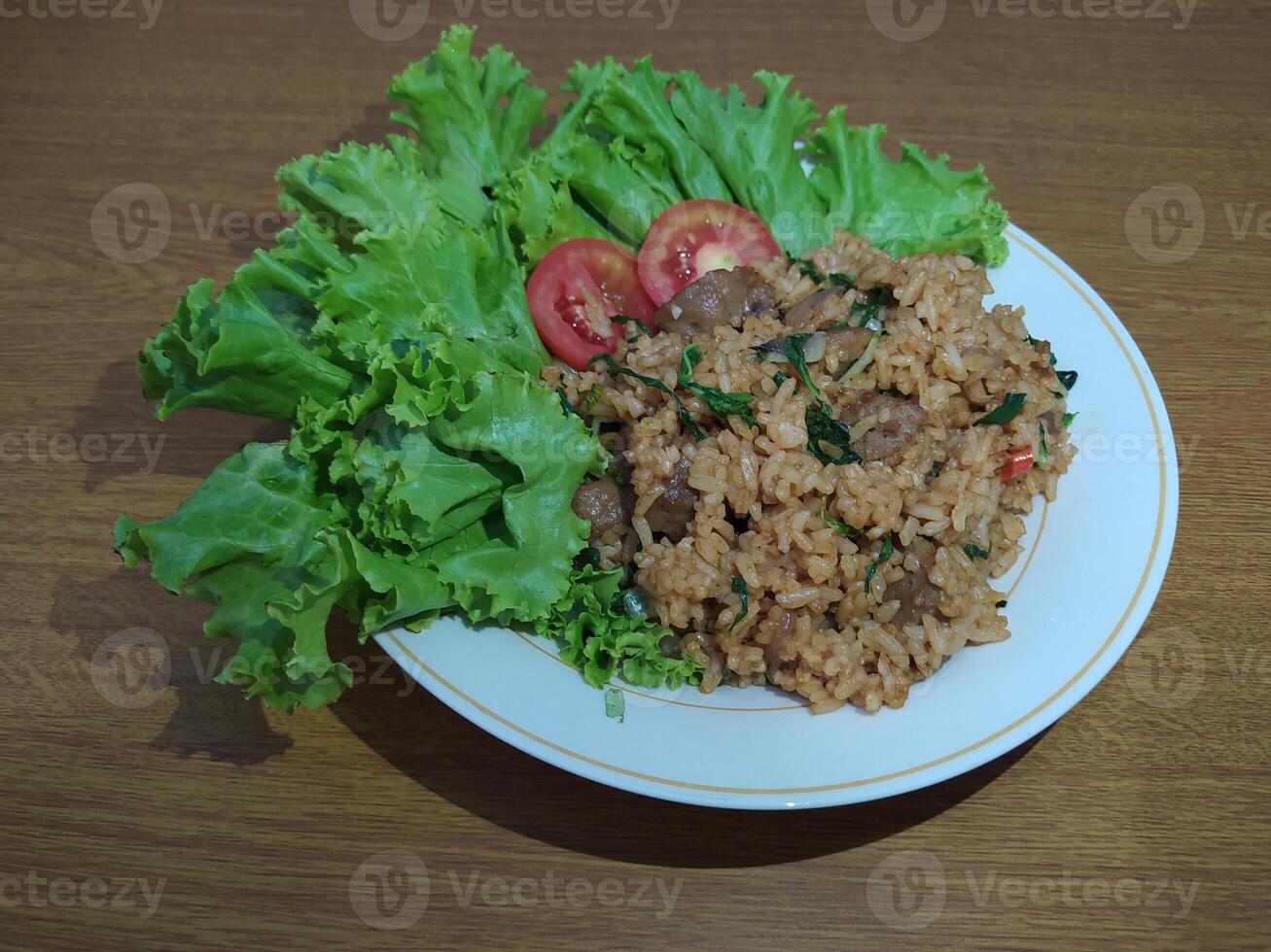 Delicious Indonesian fried rice nasi goreng with lots of lettuce, mustard greens and tomatoes served on a white plate photo