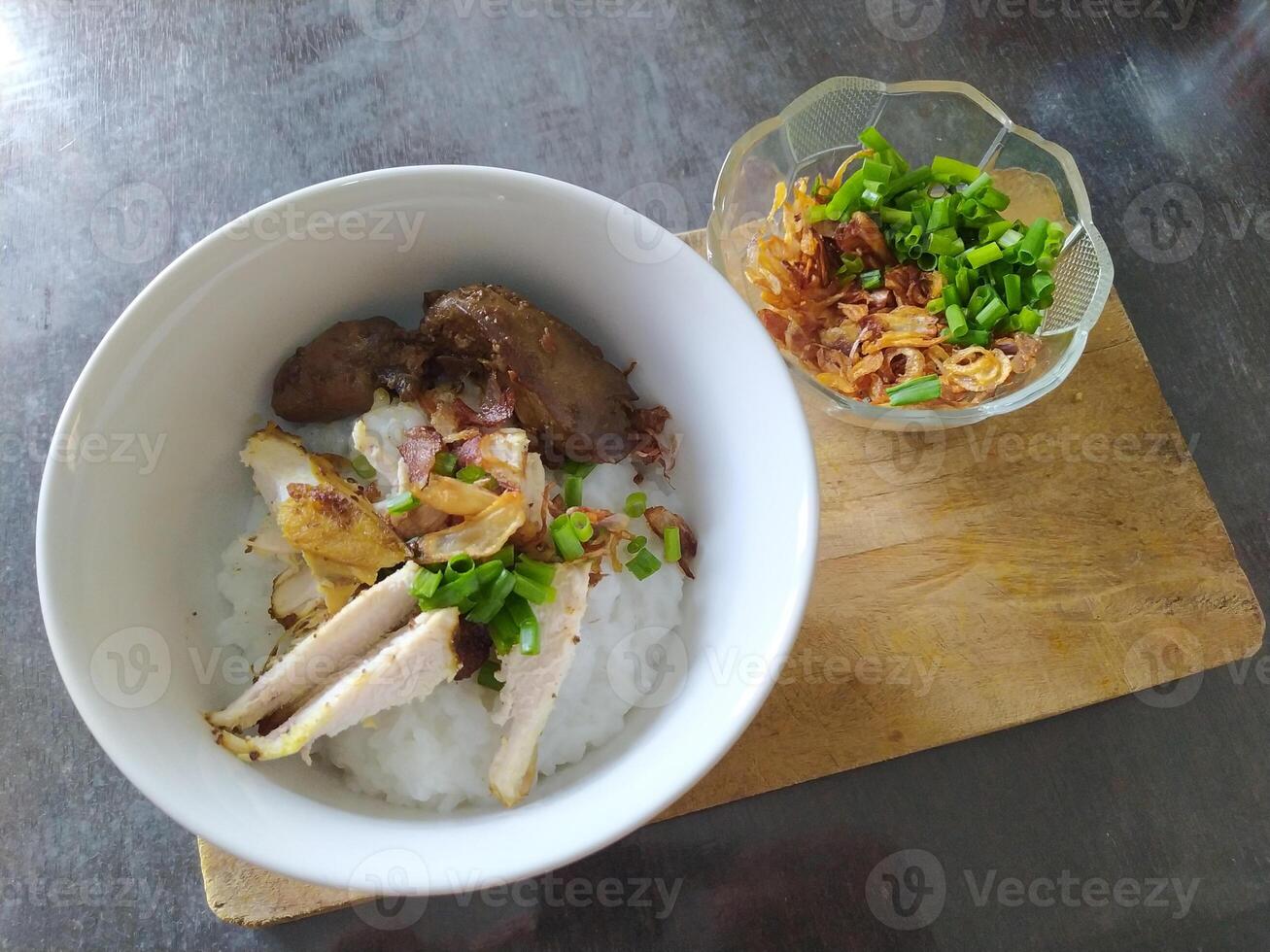 Indonesian chicken porridge served in a ceramic bowl on a wooden coaster photo