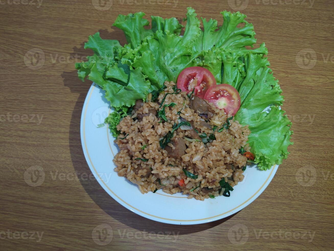 Delicious Indonesian fried rice nasi goreng with lots of lettuce, mustard greens and tomatoes served on a white plate photo