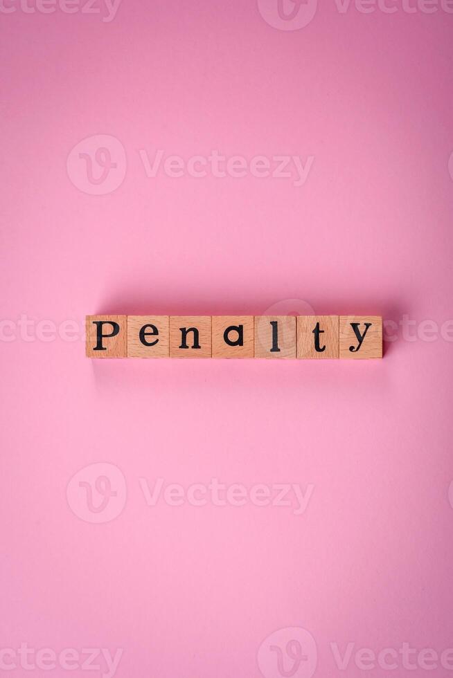 The inscription Penalty made up of wooden cubes on a plain background photo