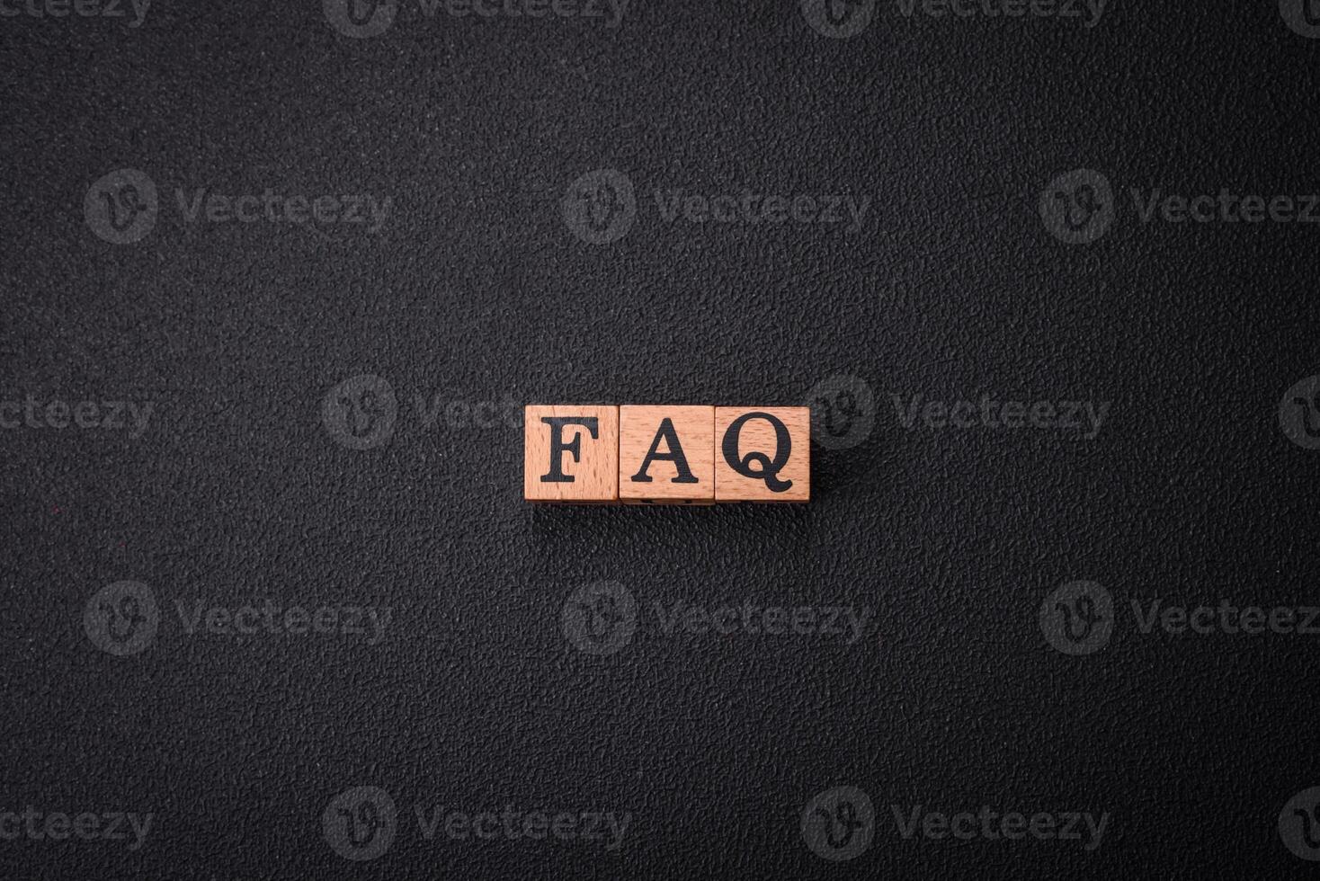 The inscription FAQ made up of wooden cubes on a plain background photo