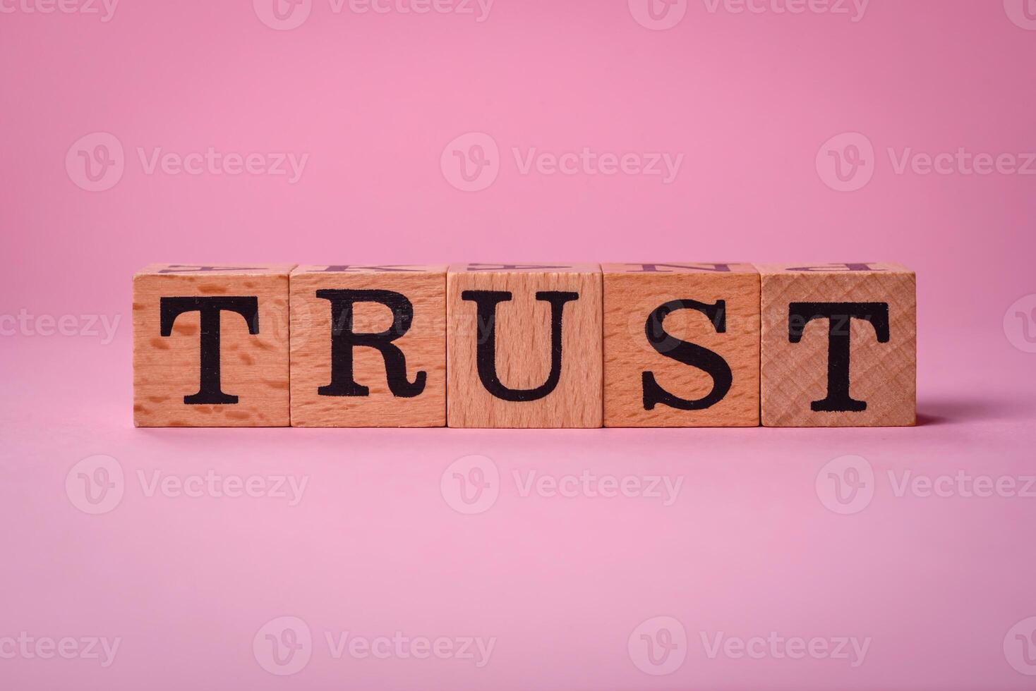 The inscription Trust made of wooden cubes on a plain background photo