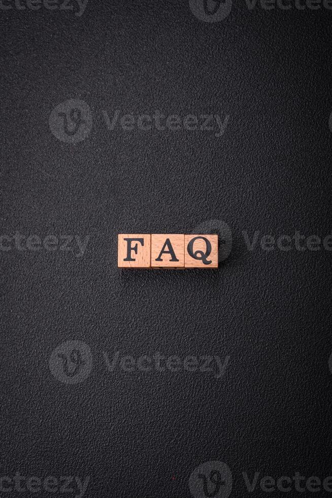 The inscription FAQ made up of wooden cubes on a plain background photo
