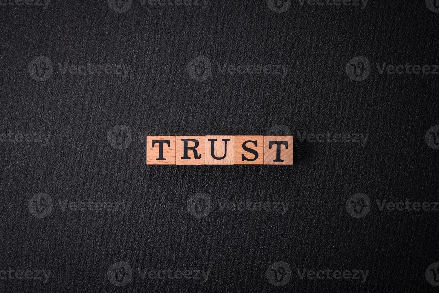 The inscription Trust made of wooden cubes on a plain background photo