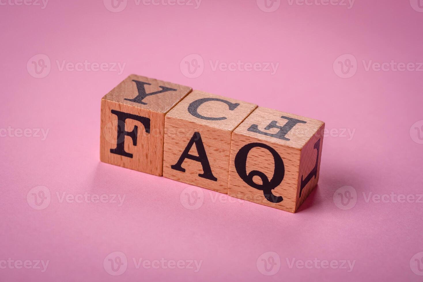 The inscription FAQ made up of wooden cubes on a plain background photo
