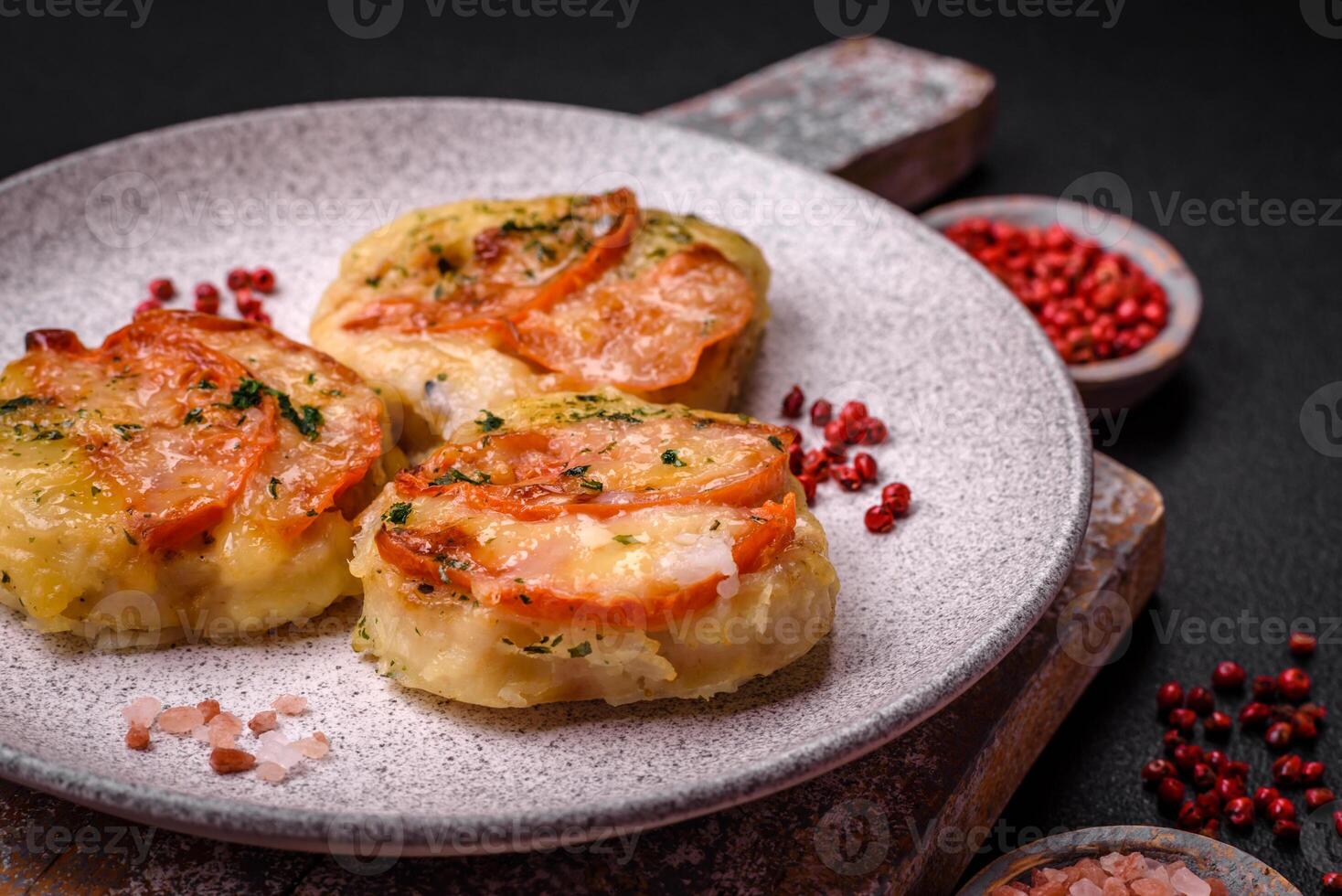 Delicious baked fish fillet with cheese, tomatoes, salt, spices and herbs photo