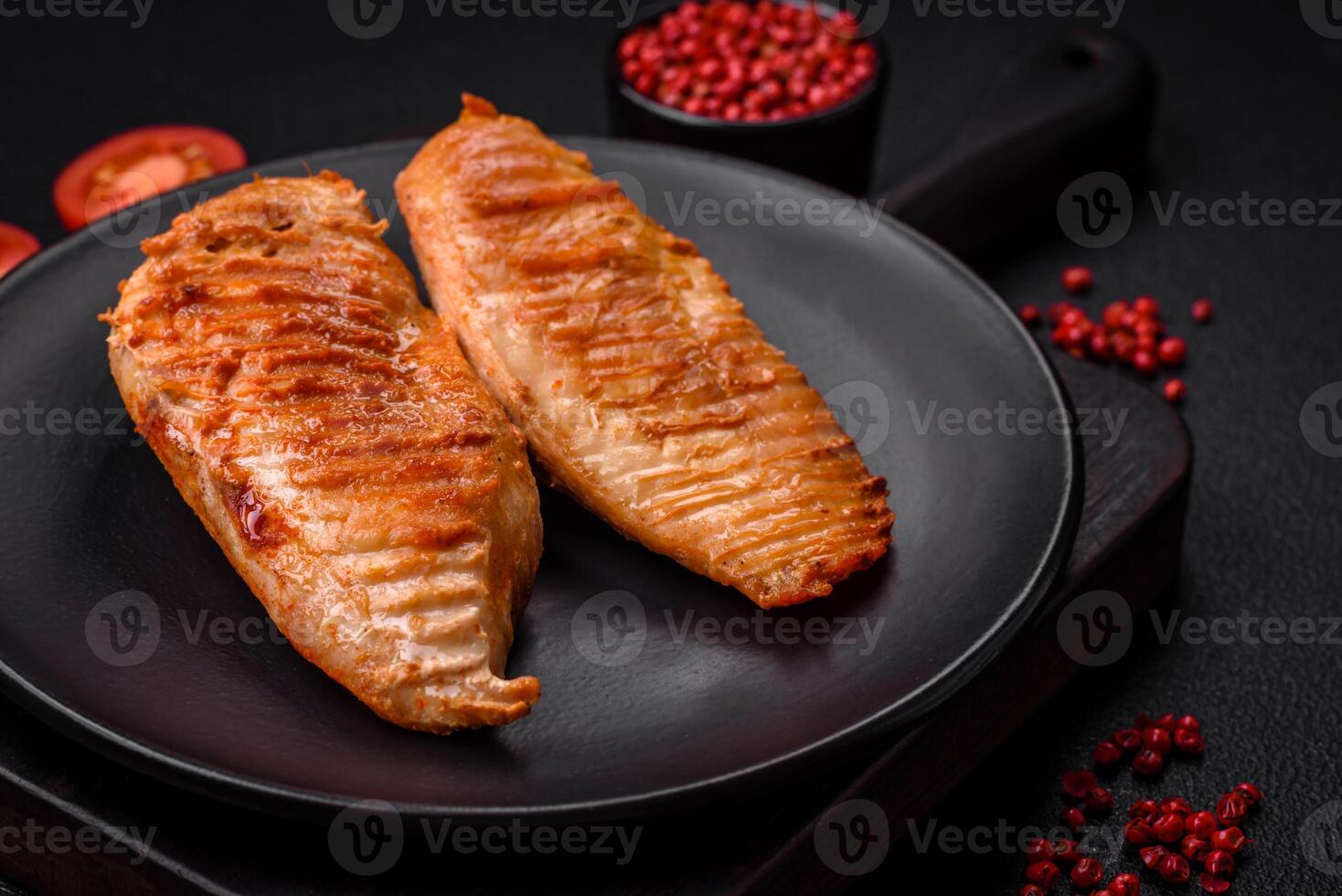 Delicious fresh grilled chicken fillet with spices and herbs on a dark concrete background photo