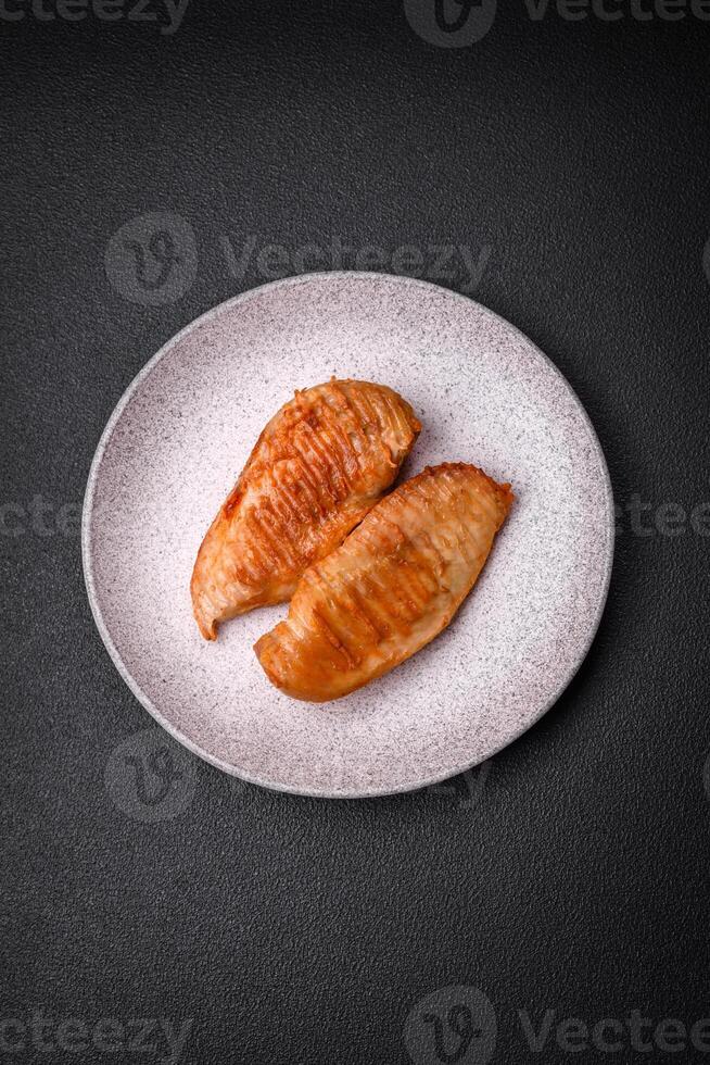 Delicious fresh grilled chicken fillet with spices and herbs on a dark concrete background photo