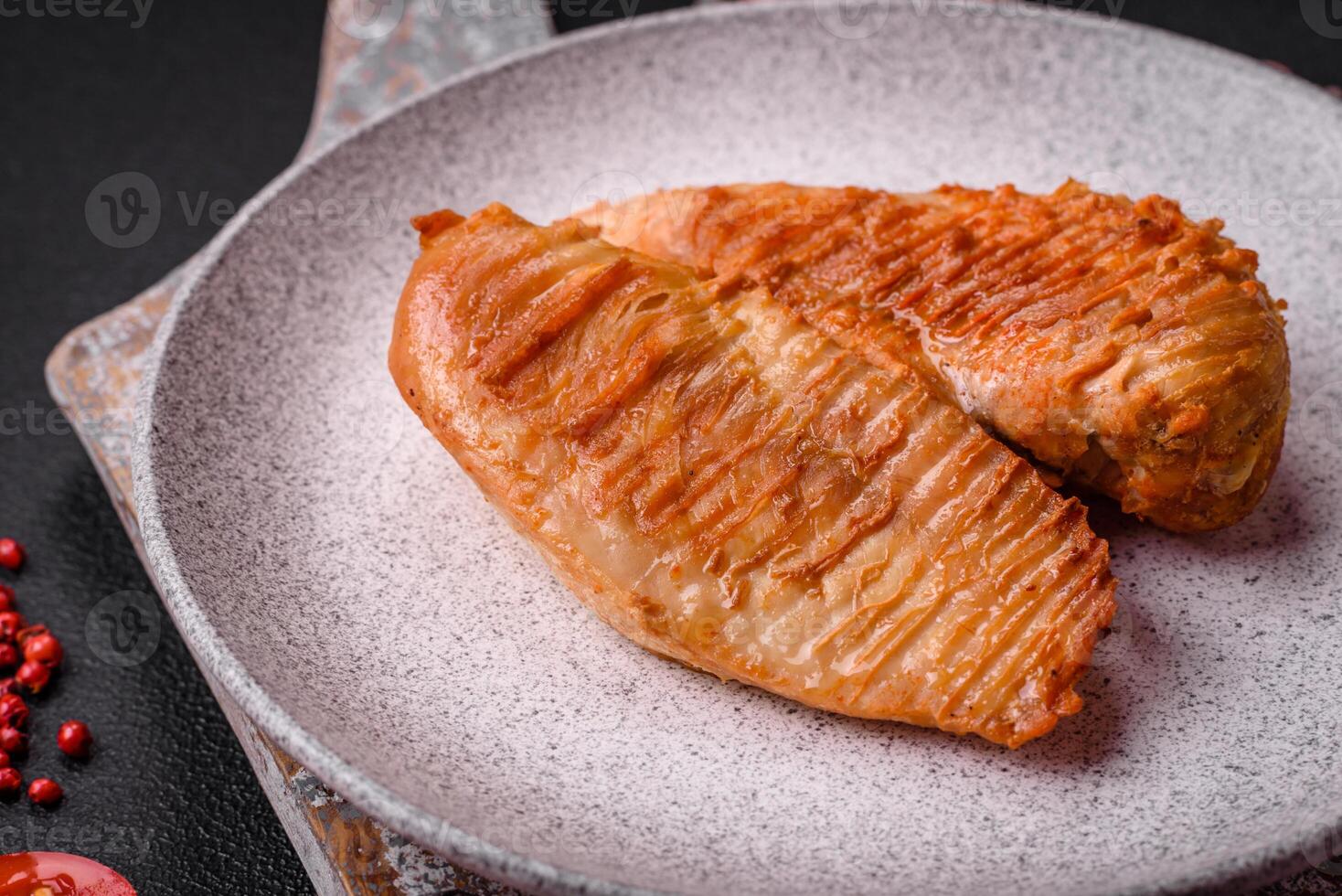 Delicious fresh grilled chicken fillet with spices and herbs on a dark concrete background photo