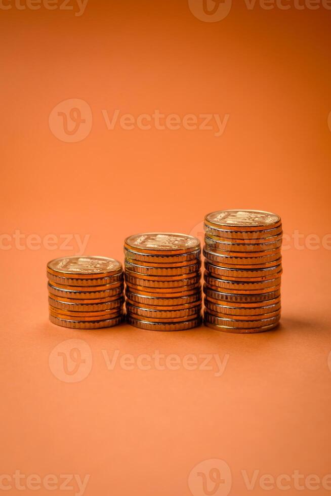 Round metal yellow coins folded in the form of columns on a plain colored background photo