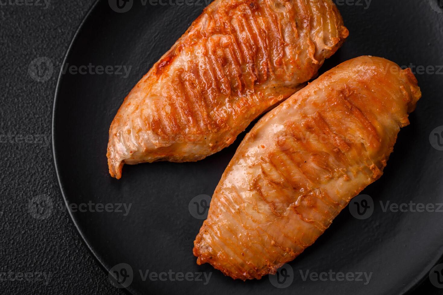 Delicious fresh grilled chicken fillet with spices and herbs on a dark concrete background photo