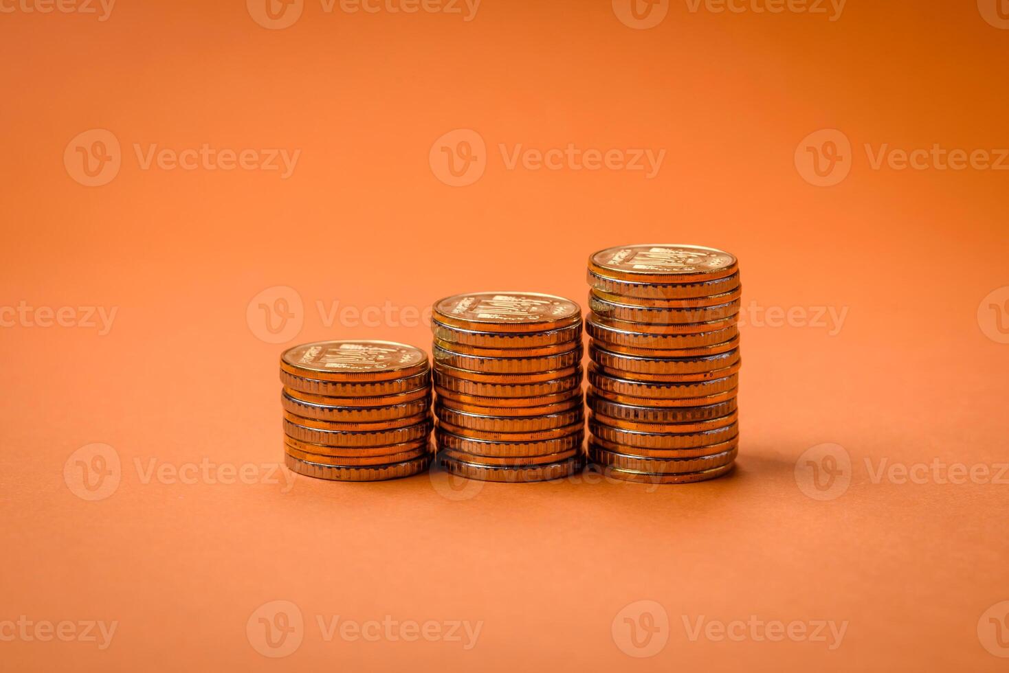 Round metal yellow coins folded in the form of columns on a plain colored background photo